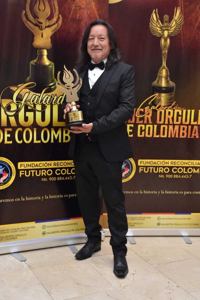 orlando flores sosteniendo el premio galardon orgullo de colombia